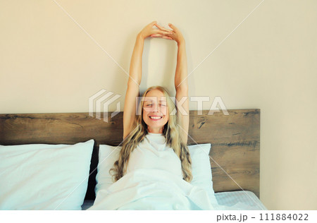 Healthy sleep, relaxed middle aged woman wakes up lying on the bed in bedroom at home Healthy sleep, relaxed middle aged woman wakes up lying on the bed in bedroom at home 111884022
