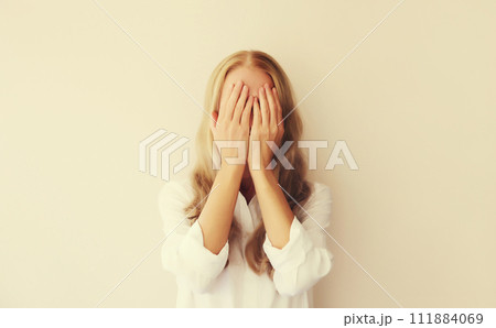 Upset sad crying young woman covering her eyes with her hands while experiencing mental 111884069