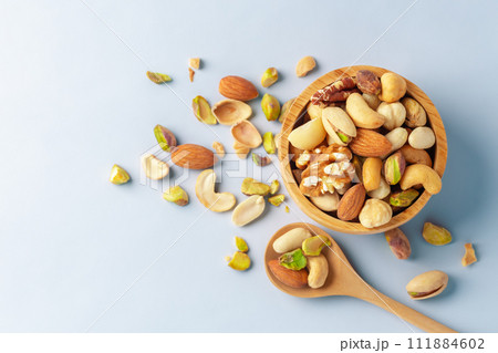 Nuts mixed in wooden bowl with spoon on blue background, top view, copy space 111884602