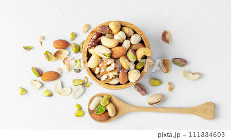 Various nuts in wooden bowl with spoon on white  background, top view 111884603