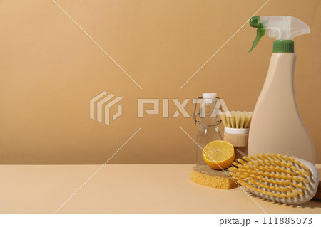 Brushes, sponge, lemon and bottles on beige background, space for text 111885073