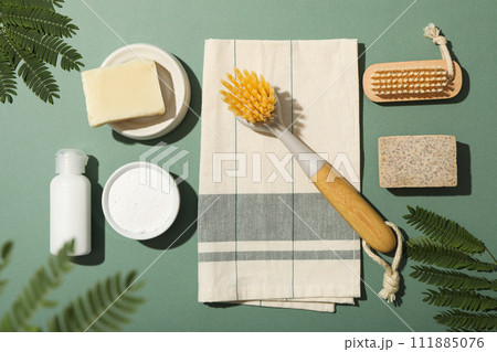 Towel, brushes, natural cleaning products and branches on green background, top view Towel, brushes, natural cleaning products and branches on green background, top view 111885076