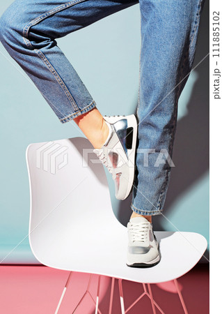 Summer women's shoes on a colored background. The model is standing on a chair. Light shoes. Summer women's shoes on a colored background. The model is standing on a chair. Light shoes. 111885102