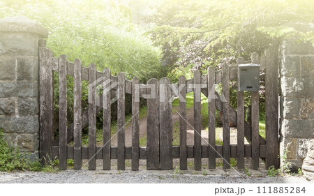 Wooden gate in a stone wall on a farm on sunlight 111885284