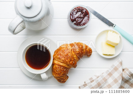 Baked tasty croissant and coffee cup on white table. Top view. 111885600