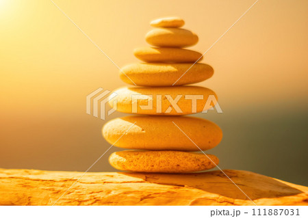 Pyramid stones on the seashore on a sunny day on the blue sea background. Happy holidays. Pebble beach, calm sea, travel destination. Concept of happy vacation on the sea, meditation, spa, calmness. Pyramid stones on the seashore on a sunny day on the blue sea background. Happy holidays. Pebble beach, calm sea, travel destination. Concept of happy vacation on the sea, meditation, spa, calmness. 111887031