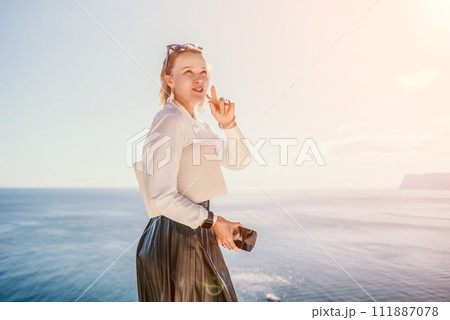 Digital nomad, Business woman working on laptop by the sea. Pretty lady typing on computer by the sea at sunset, makes a business transaction online from a distance. Freelance, remote work on vacation Digital nomad, Business woman working on laptop by the sea. Pretty lady typing on computer by the sea at sunset, makes a business transaction online from a distance. Freelance, remote work on vacation 111887078