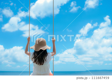 海岸にあるブランコに座って海を眺める少女 111887459