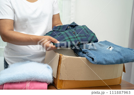 Donation box with used clothes at home to support help for poor people in the world. 111887963