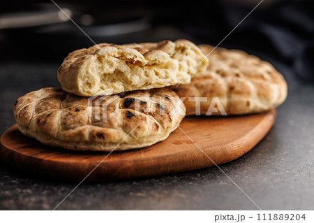Arabic flat pita bread on cutting board on black table. Arabic flat pita bread on cutting board on black table. 111889204