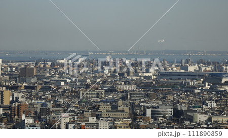 川崎市役所展望フロアから見た川崎市の市街地と沿岸部の工業地帯、羽田空港に向かう飛行機 111890859