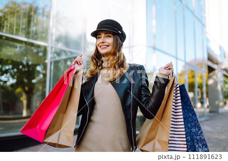 Stylish woman with shopping bags walks through the city streets. Spring Style. Stylish woman with shopping bags walks through the city streets. Spring Style. 111891623