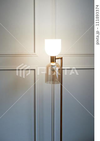 Interesting minimalist lamp in English style on the background of a gray wall with decorative panels. Minimalism, consistent style Interesting minimalist lamp in English style on the background of a gray wall with decorative panels. Minimalism, consistent style 111893374