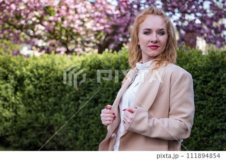 Serious young woman in white blouse looking to the camera. Woman of European appearance. Successful business woman in spring park. 111894854