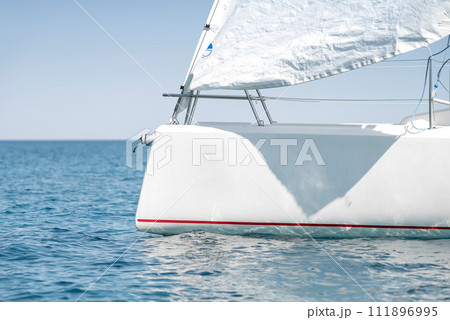 Stern with a sail of a white sport keelboat yacht Stern with a sail of a white sport keelboat yacht 111896995