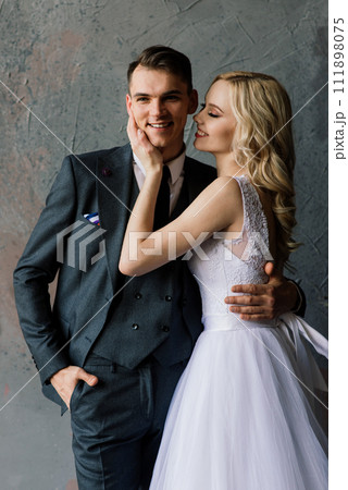 Cute wedding couple in the interior of a classic studio decorated. They kiss and hug each other. 111898075