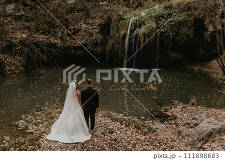 bride hugs groom near small pond lake river waterfall Burbun bride hugs groom near small pond lake river waterfall Burbun 111898683
