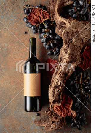 Bottle of red wine with blue grapes on a rusty background. 111898921