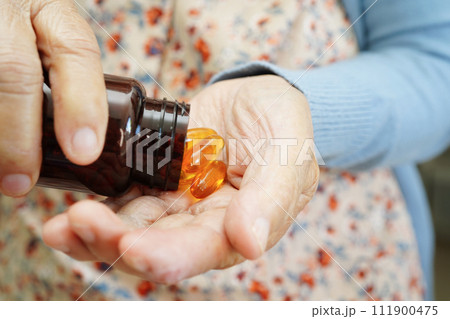 Asian elderly woman holding pill drug in hand, strong healthy medical concept. 111900475