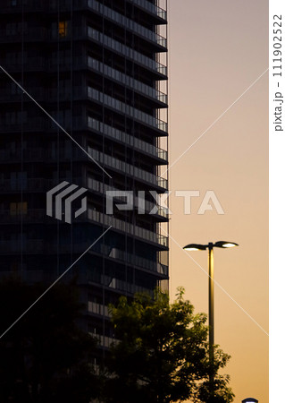 夕暮れの空と高層マンションと明かりの灯った街灯 111902522