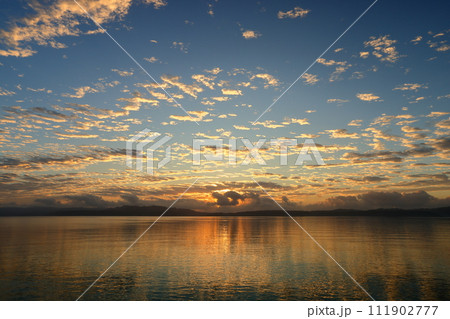 沖縄県国頭郡今帰仁村　古宇利島と沖縄本島方面の屋我地島を結ぶ古宇利大橋から古宇利ブルー越しの朝陽 111902777