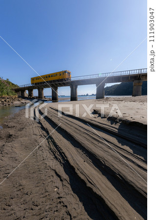 砂模様と青空の下鉄橋走るJR九州日南線黄色いDLキハ40 111903047