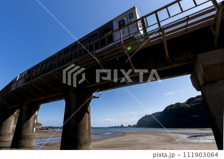 干潮での砂模様と青空、海の島々光景なか走るJR九州日南線観光列車海幸山幸 111903064