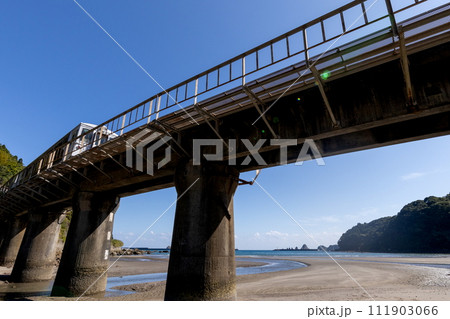干潮での砂模様と青空、海の島々光景なか走るJR九州日南線観光列車海幸山幸 111903066