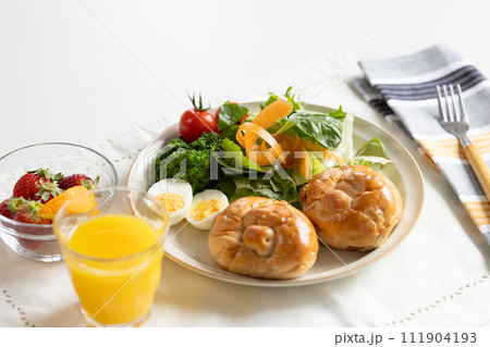 朝食　テーブルに置かれたパンとサラダ 111904193