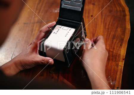Hand of photographer rewinding knob to tighten film to camera Hand of photographer rewinding knob to tighten film to camera 111906541