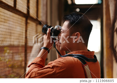 Photographer walking around old town area and taking pictures of abandoned buildings 111906605