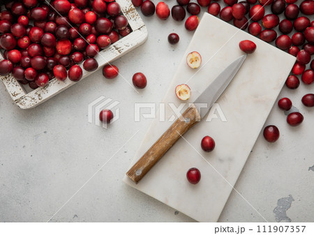 Red dried sweet and sour cranberries in glass jar on light background. Red dried sweet and sour cranberries in glass jar on light background. 111907357
