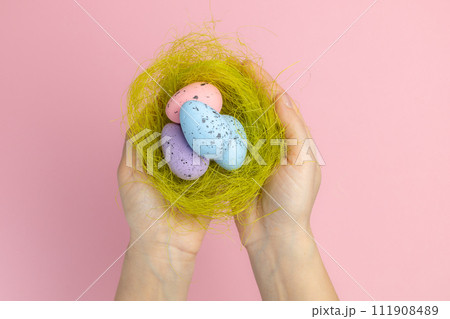 Female hands holding a nest with the Easter eggs. 111908489