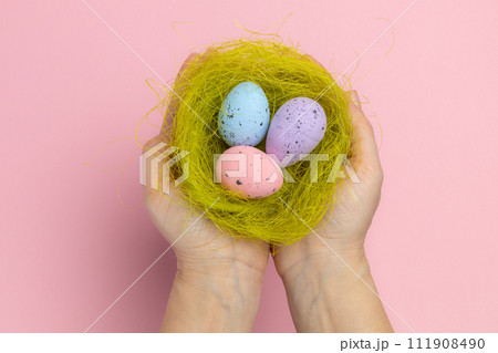 Female hands holding a nest with the Easter eggs. Female hands holding a nest with the Easter eggs. 111908490