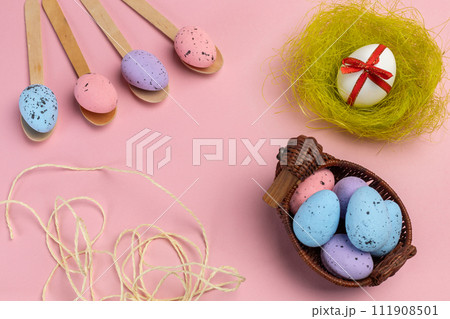 Colored Easter eggs on wooden spoons and in a wicker basket with a nest. Colored Easter eggs on wooden spoons and in a wicker basket with a nest. 111908501