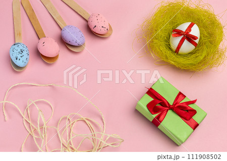 Colored Easter eggs on wooden spoons with a nest and a gift box. Colored Easter eggs on wooden spoons with a nest and a gift box. 111908502