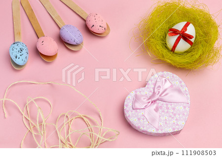 Colored Easter eggs on wooden spoons with a nest and a gift box. Colored Easter eggs on wooden spoons with a nest and a gift box. 111908503