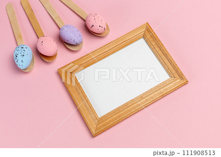 Colored Easter eggs on wooden spoons with a photo frame. Colored Easter eggs on wooden spoons with a photo frame. 111908513