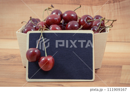 Fresh ripe juicy cherries in container. Dessert or snack. Copy space for text on black board Fresh ripe juicy cherries in container. Dessert or snack. Copy space for text on black board 111909167