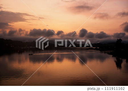 Silhouette boat sailing by wooden Mon bridge at dawn, Sangkhlaburi 111911102