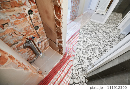 Comparison of washroom lavatory before and after renovation. Old apartment room with underfloor heating pipes and new renovated room. 111912390