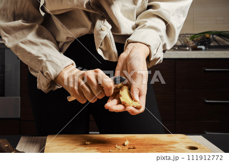 Female hands peeling ginger with spoon Female hands peeling ginger with spoon 111912772