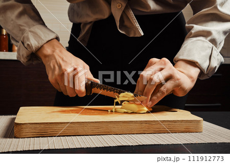 Unrecognizable woman slicing ginger root into thin strips Unrecognizable woman slicing ginger root into thin strips 111912773