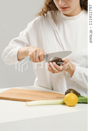 Unrecognizable woman cutting fresh avocado into halves 111912797