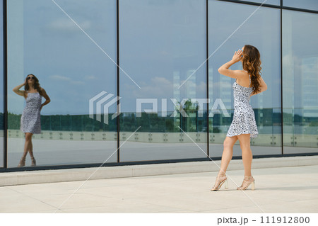 Woman posing in front of glass wall of a building Woman posing in front of glass wall of a building 111912800