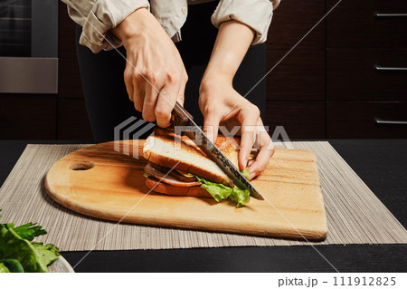 Unrecognizable woman cuts on half sandwich 111912825