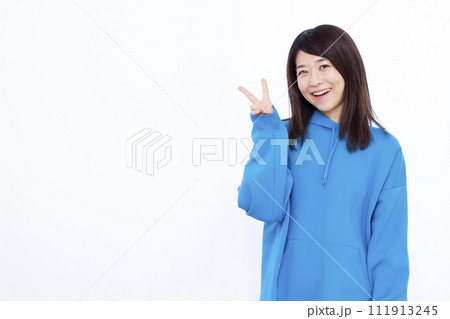 ピースサインをしている青いパーカーを着た女性の写真素材 [111913245