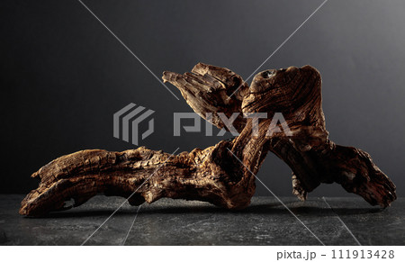Old dry wooden snag on a black stone table. 111913428