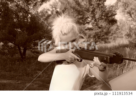 A young beautiful blonde girl shoots from a rifle. AI-generated item. A young beautiful blonde girl shoots from a rifle. AI-generated item. 111913534