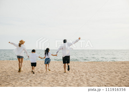 A heartening family scene on the beach parents holding hands running and jumping with their children in holiday laughter. Illustrating the happiness and togetherness of a carefree beach vacation. A heartening family scene on the beach parents holding hands running and jumping with their children in holiday laughter. Illustrating the happiness and togetherness of a carefree beach vacation. 111916356